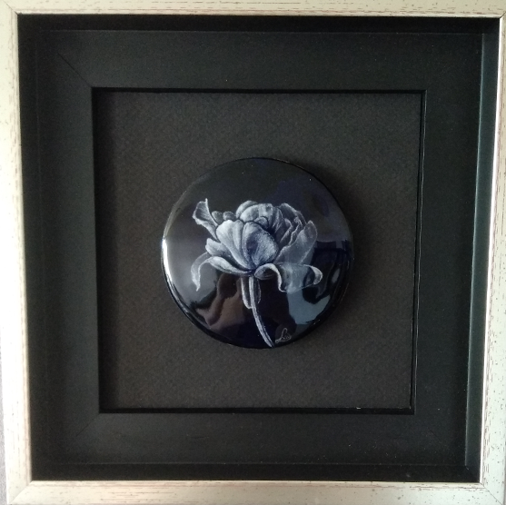 Tableau émaillé selon la technique de la grisaille. émail peint. Coupelle représentant une fleur ouverte en noir et blanc. Cadre noir et argent.